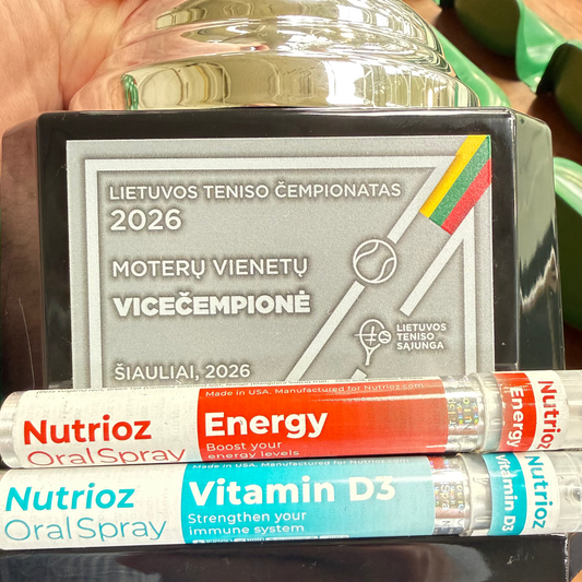 A hand holds a trophy plaque and two Nutrioz Oral Spray tubes labeled Energy and Vitamin D3 in a real-world setting with green shoes visible in the background.
